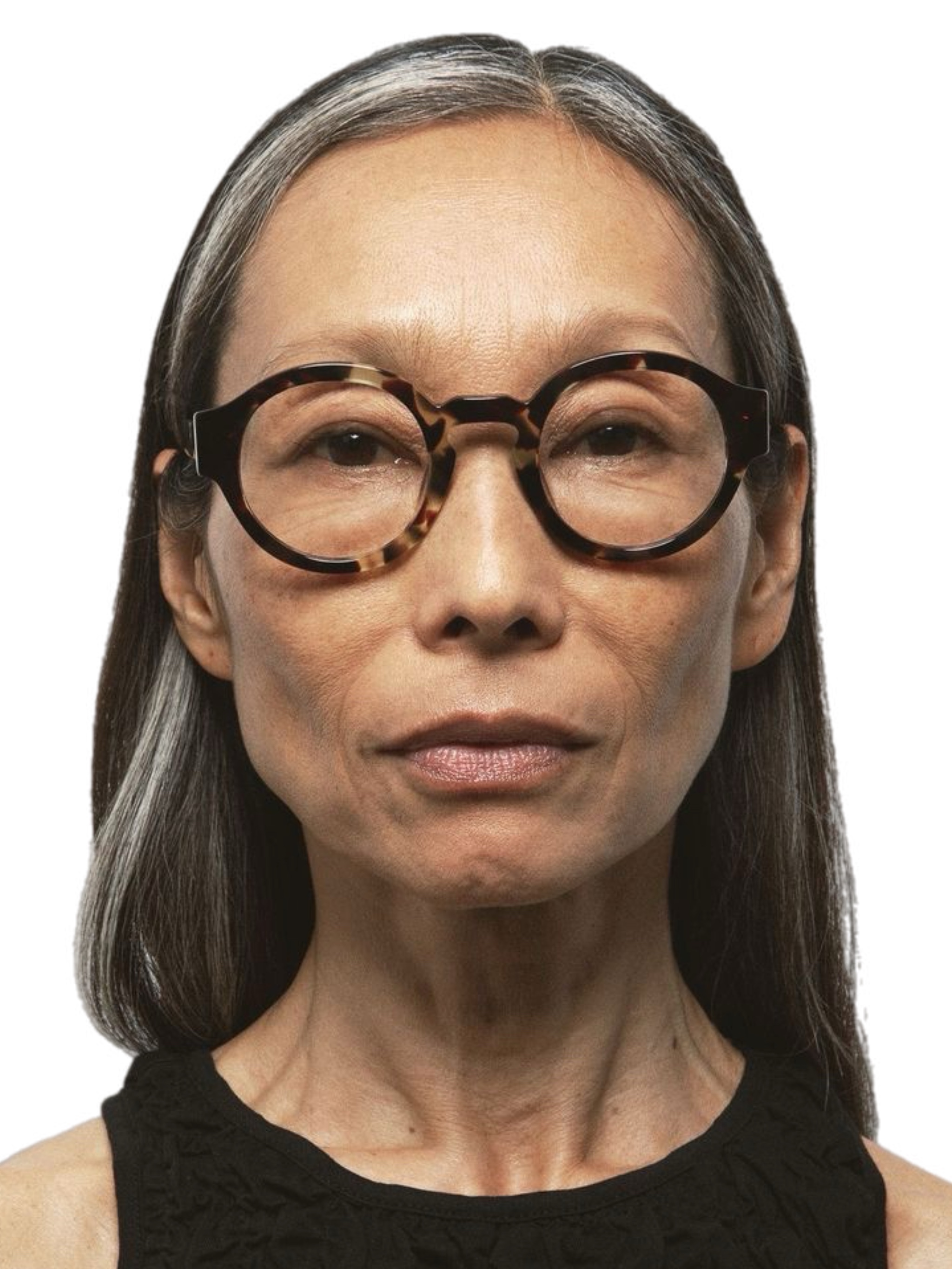 Elegant woman in her eighties with white hair, sculptural silver earrings, and a black coat, natural unretouched skin